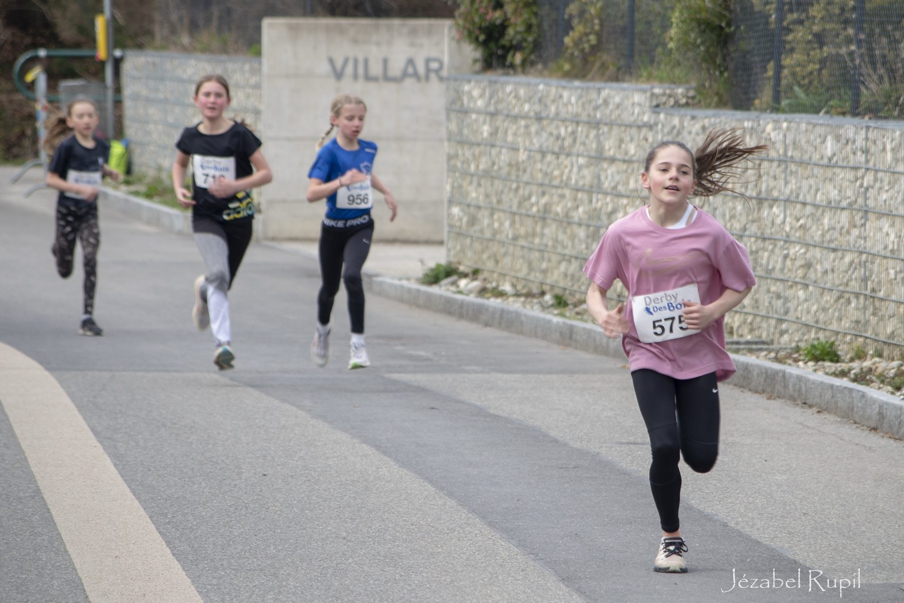 A young runner in a pink T-shirt leading her group